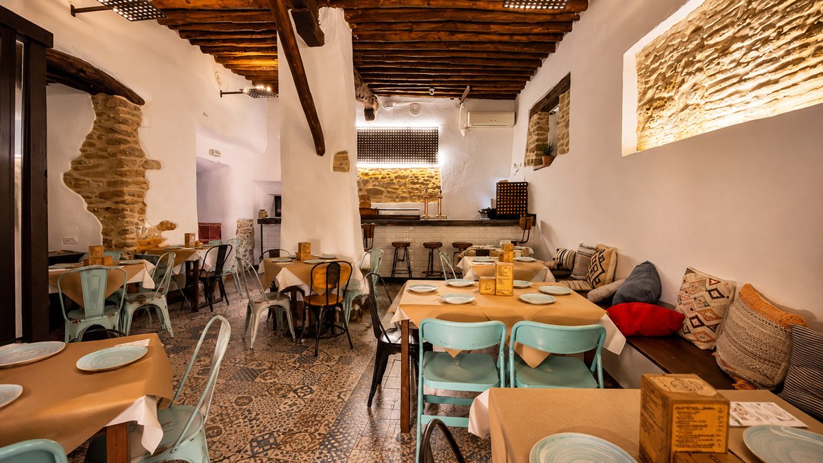 El comedor de Casa Clemente, con vigas de madera y piedra iluminada